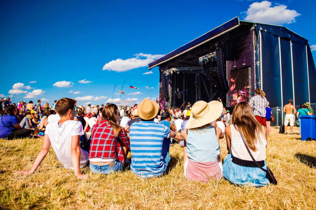 You need to rent portable toilets for festivals - a group of young people watch a music festival