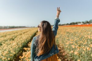 image of woman standing in a field with two fingers in a peace sign | Porta potty portable toilet rental portland oregon salem vancouver washington